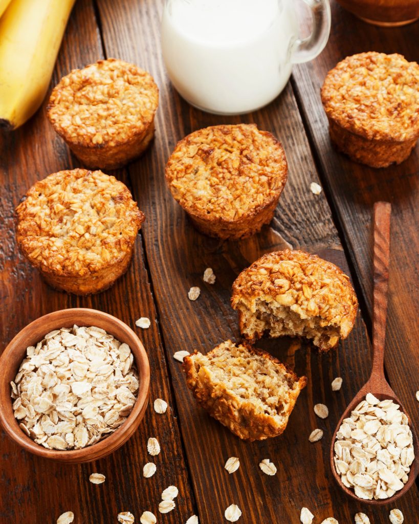 overhead shot of banana oat muffins on wooden table with milk and oats