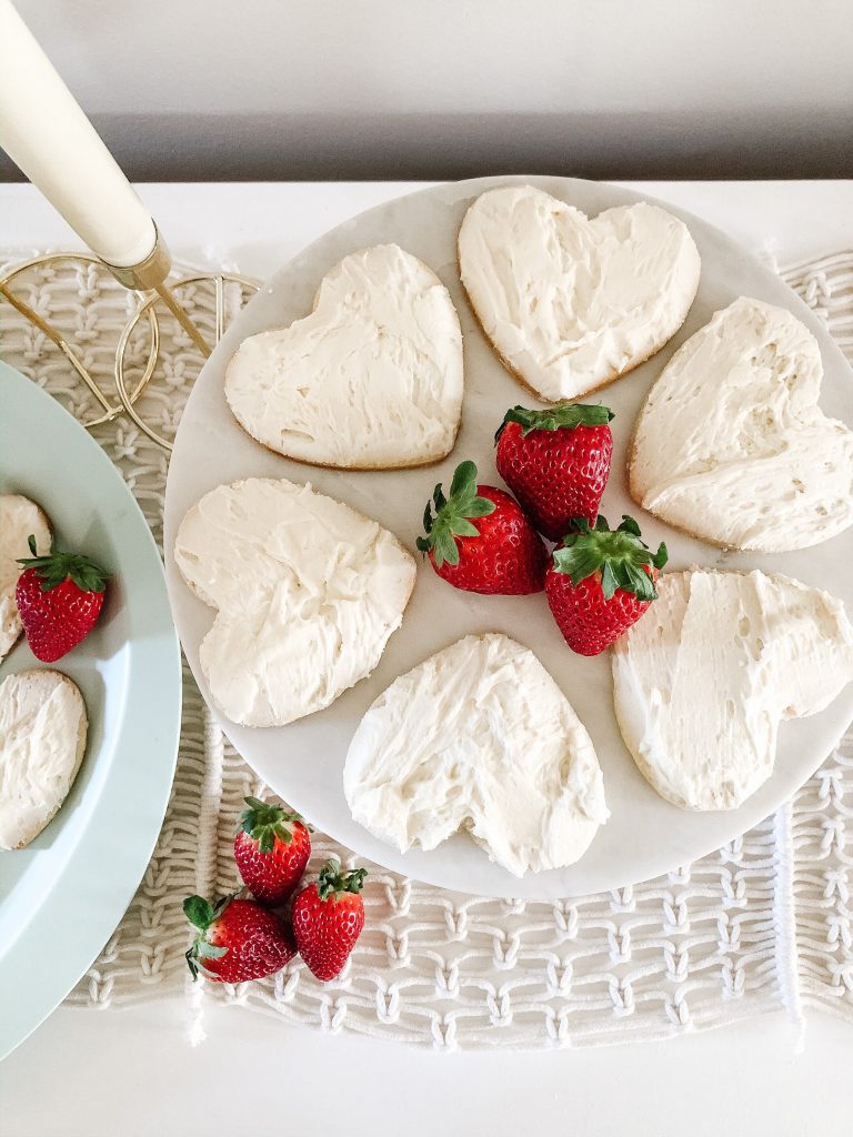 overhead image of heart-shaped sugar cookie with white icing on a cake plate