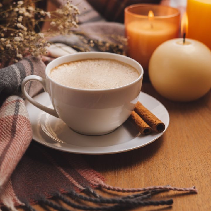 close up of latte on with cinnamon sticks and candles