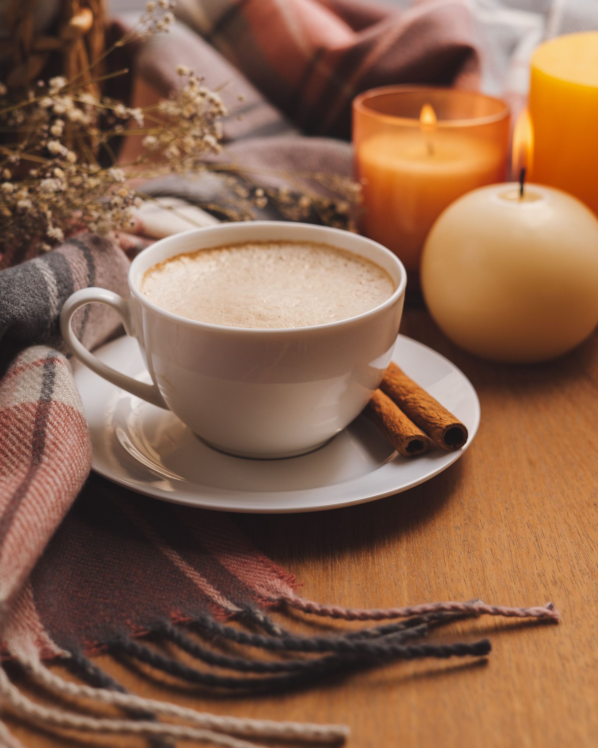 close up of latte on with cinnamon sticks and candles