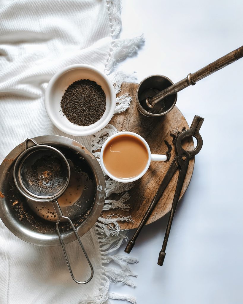 tea cup and strainer with herbs on wooden platter