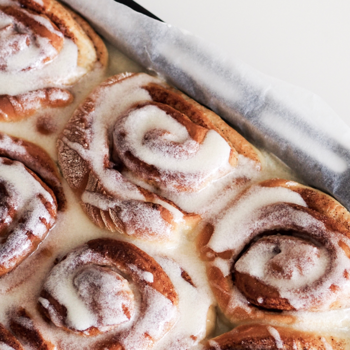 close up of iced cinnamon rolls in a pan