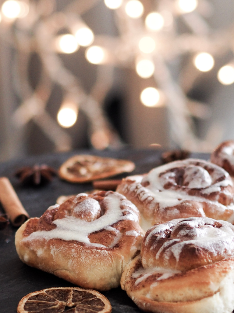 Close up of cinnamon roll on a tray with twinkle lights in the background