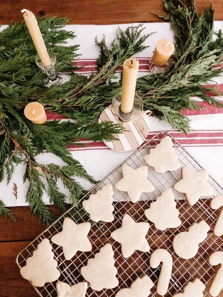 Freshly baked sugar cookies sit atop a metal cooling rack, waiting to be iced.