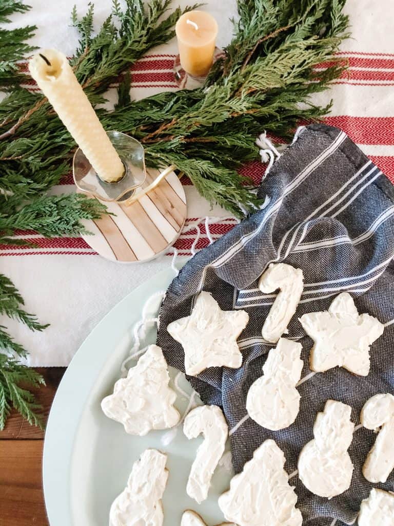 Freshly baked sugar cookies with buttercream icing are placed on a large serving platter, ready to be enjoyed.