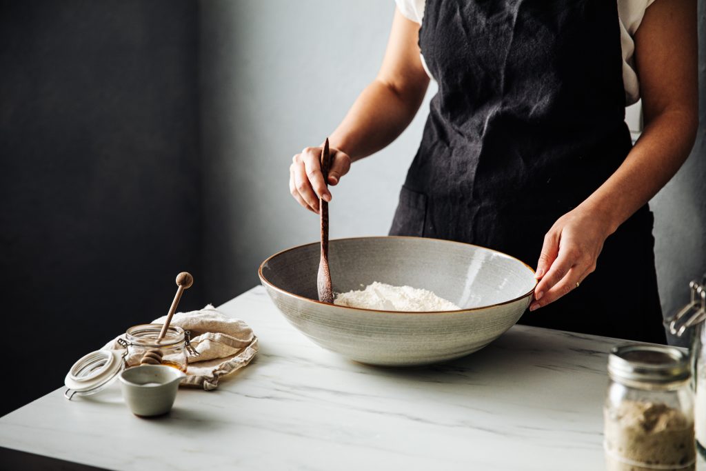 woman mixing wheat flour in bowl for bread