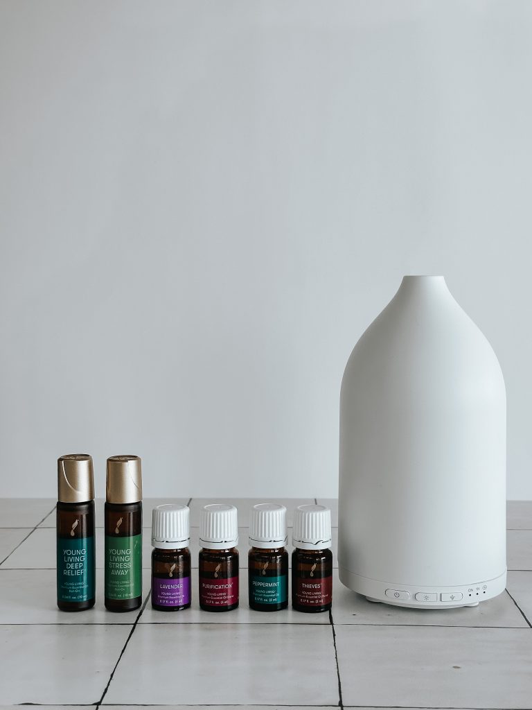 essential oils on a counter beside a white diffuser