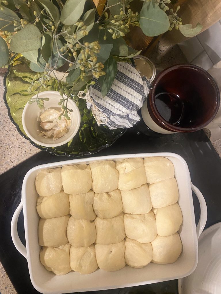 Close up of yeast rolls in a ceramic dish rising before baking