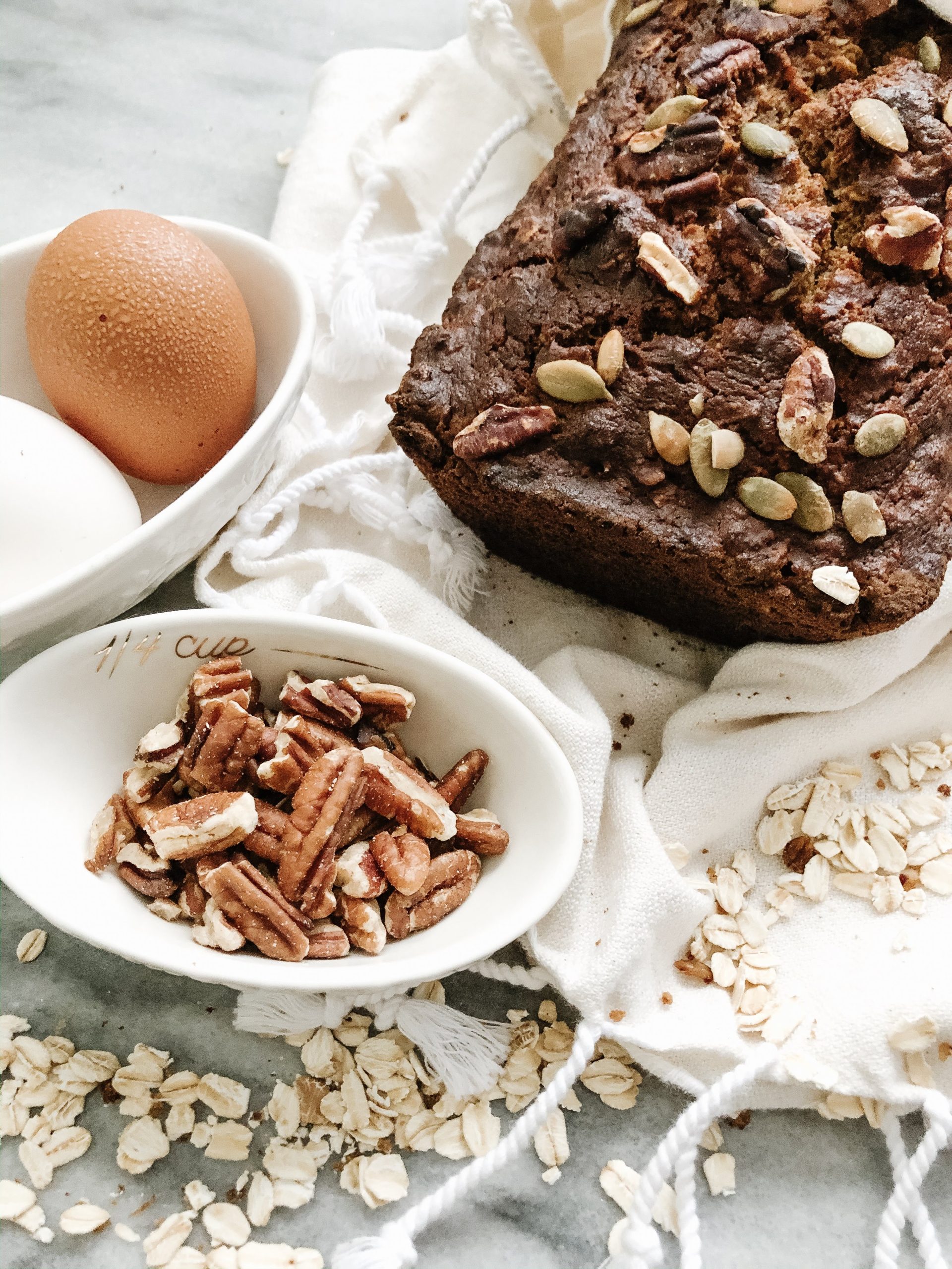 baked banana bread with eggs and pecans on a white dish towel