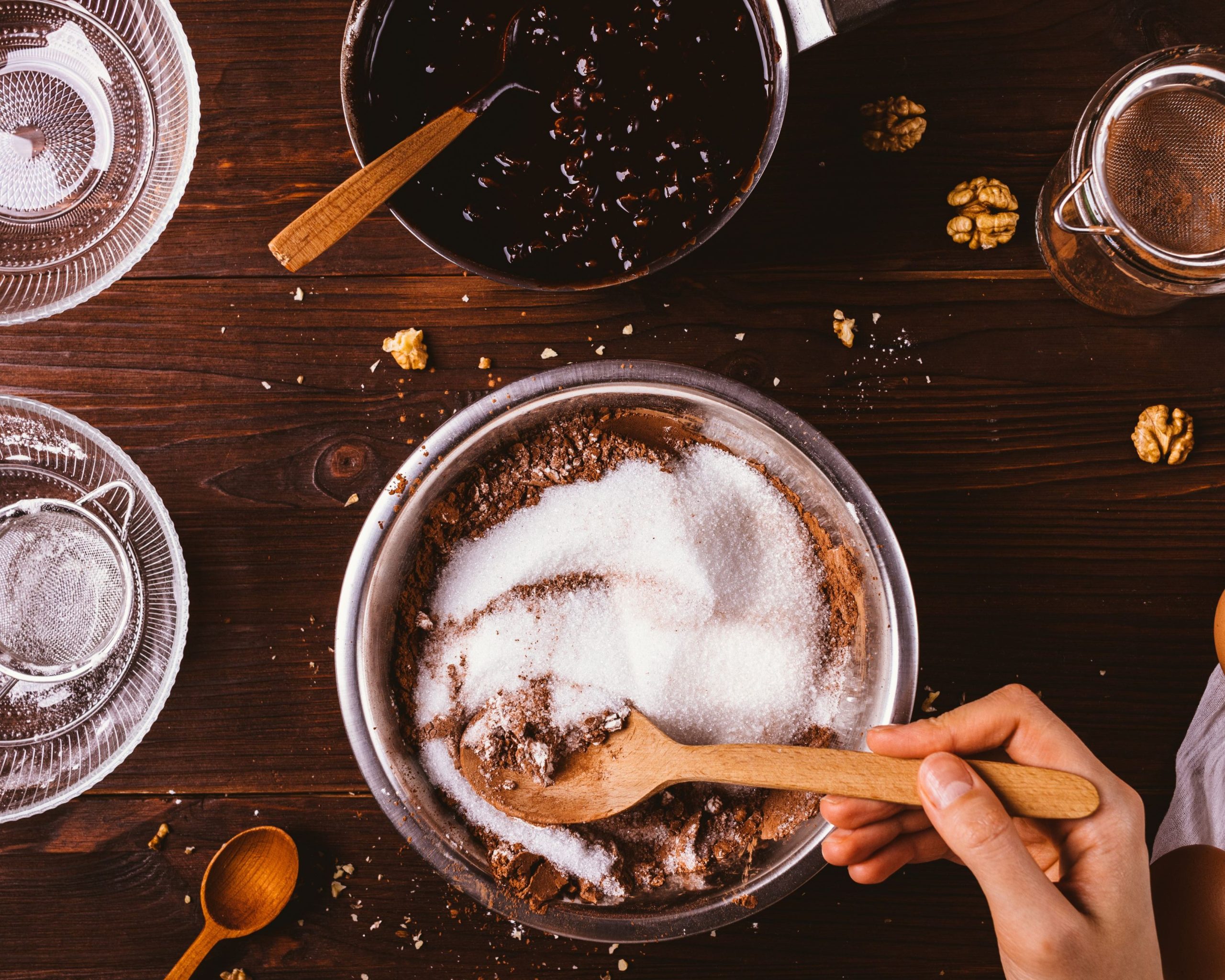 hand holding wooden spoon stirring sugar and cocoa powder