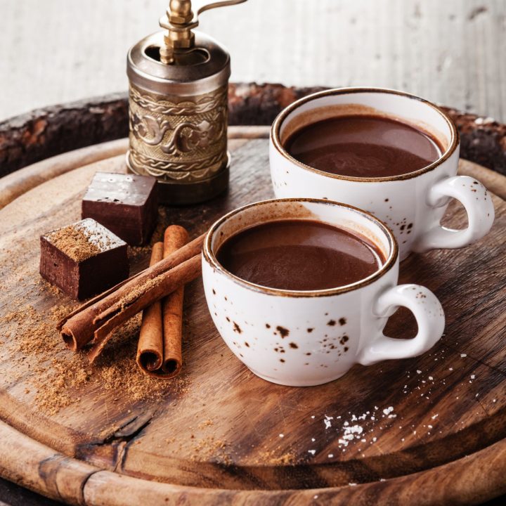 two cups of hot cocoa on a wooden tray