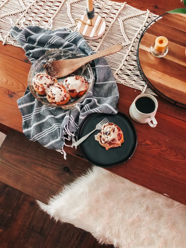 cinnamon rolls on a wooden table with a cup of coffee