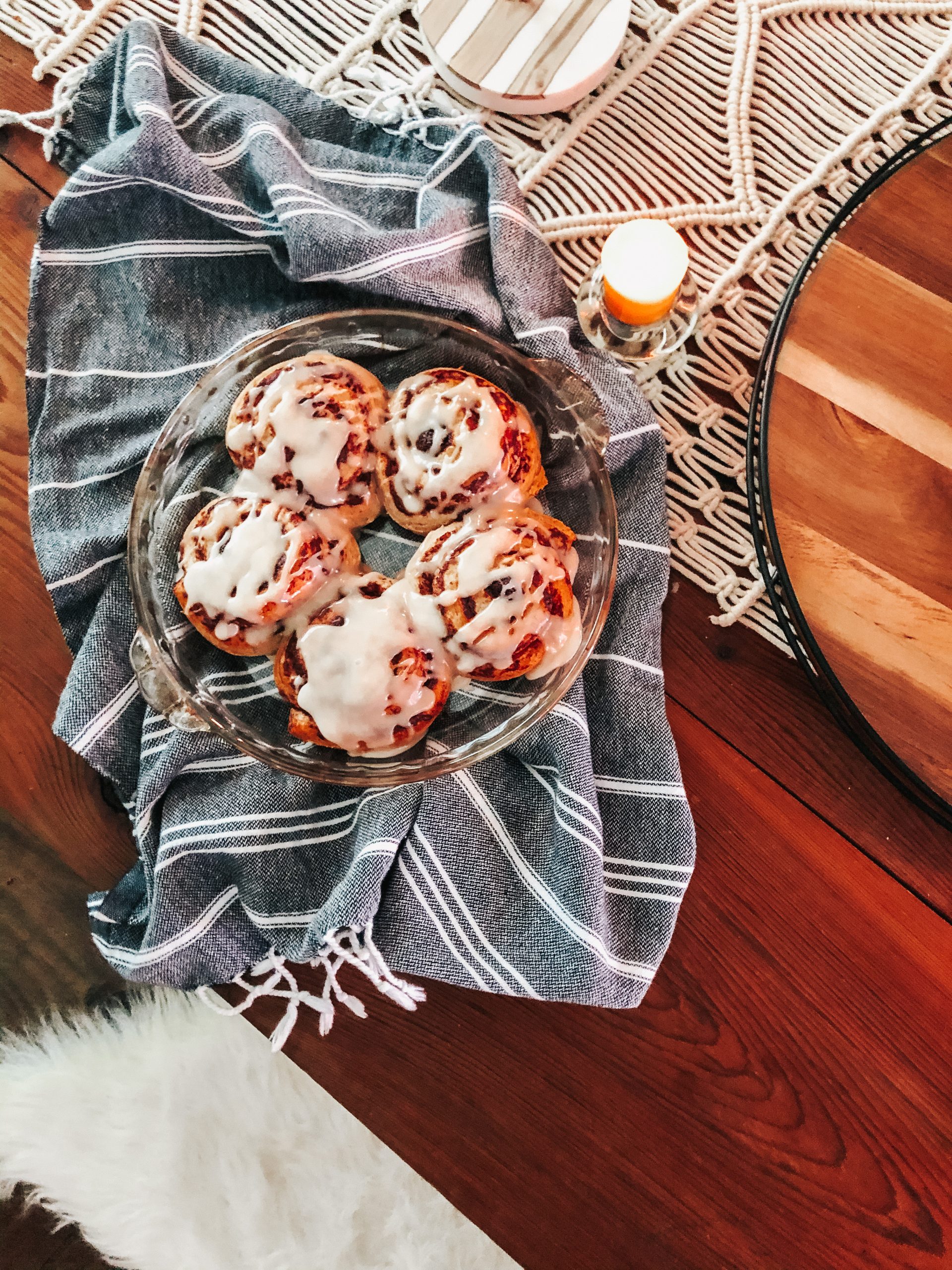 close up of iced cinnamon rolls in a dish on top of a black eta towel