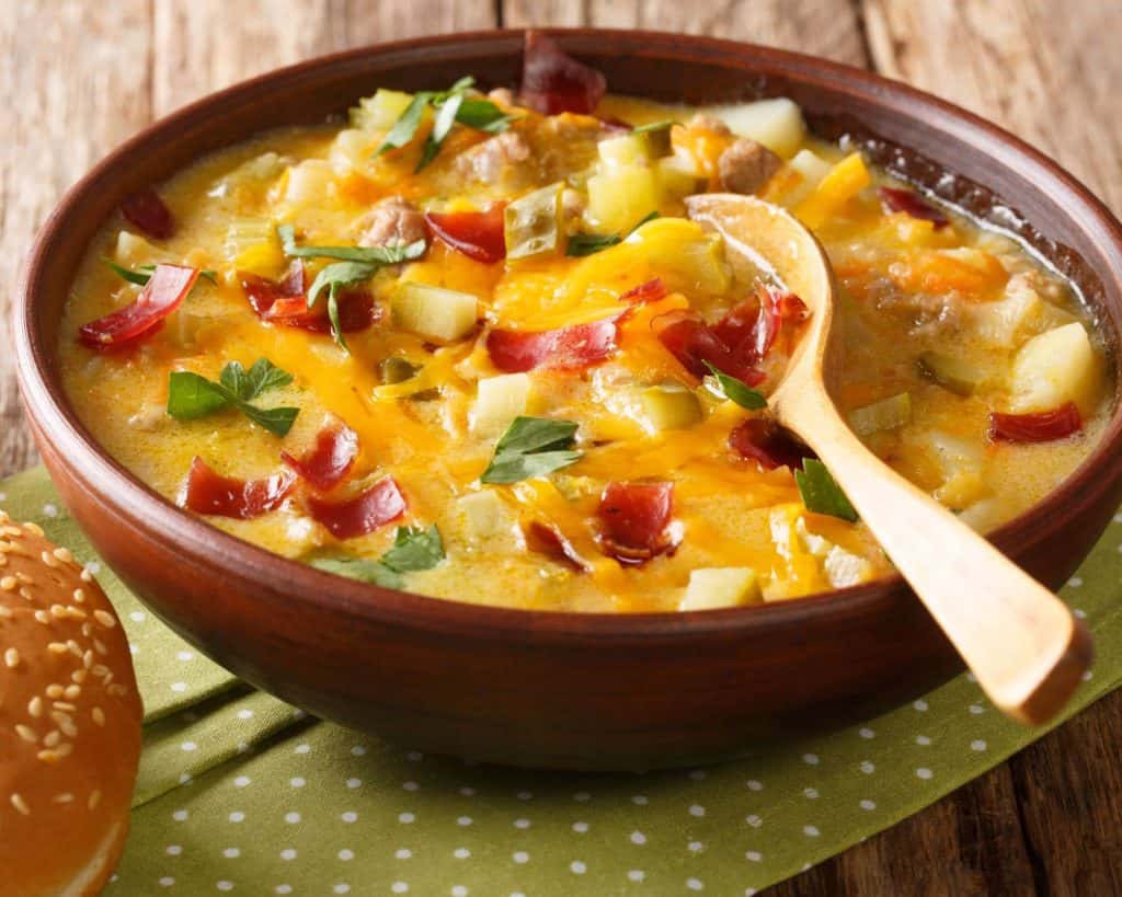 Close up of easy cheeseburger soup recipe with chives ad bacon on a green and white napkin