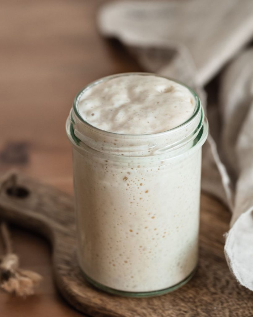 close up of bubbly, active sourdough starter in a glass jar