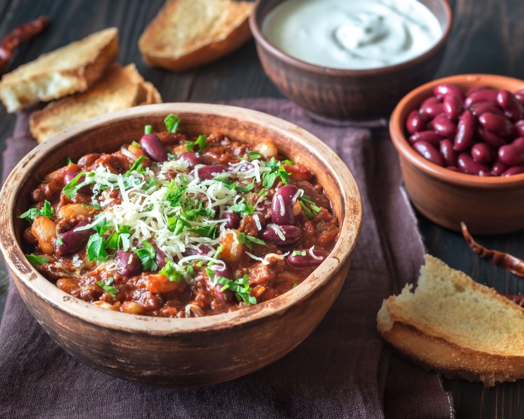 hearty chili in a wooden bowl with cheese and cilantro