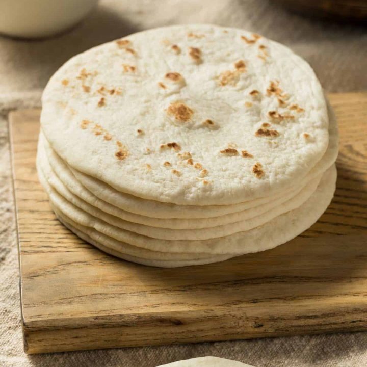 soft sourdough tortillas stacked upon a wooden cutting board, ready to be turned into something delicious!