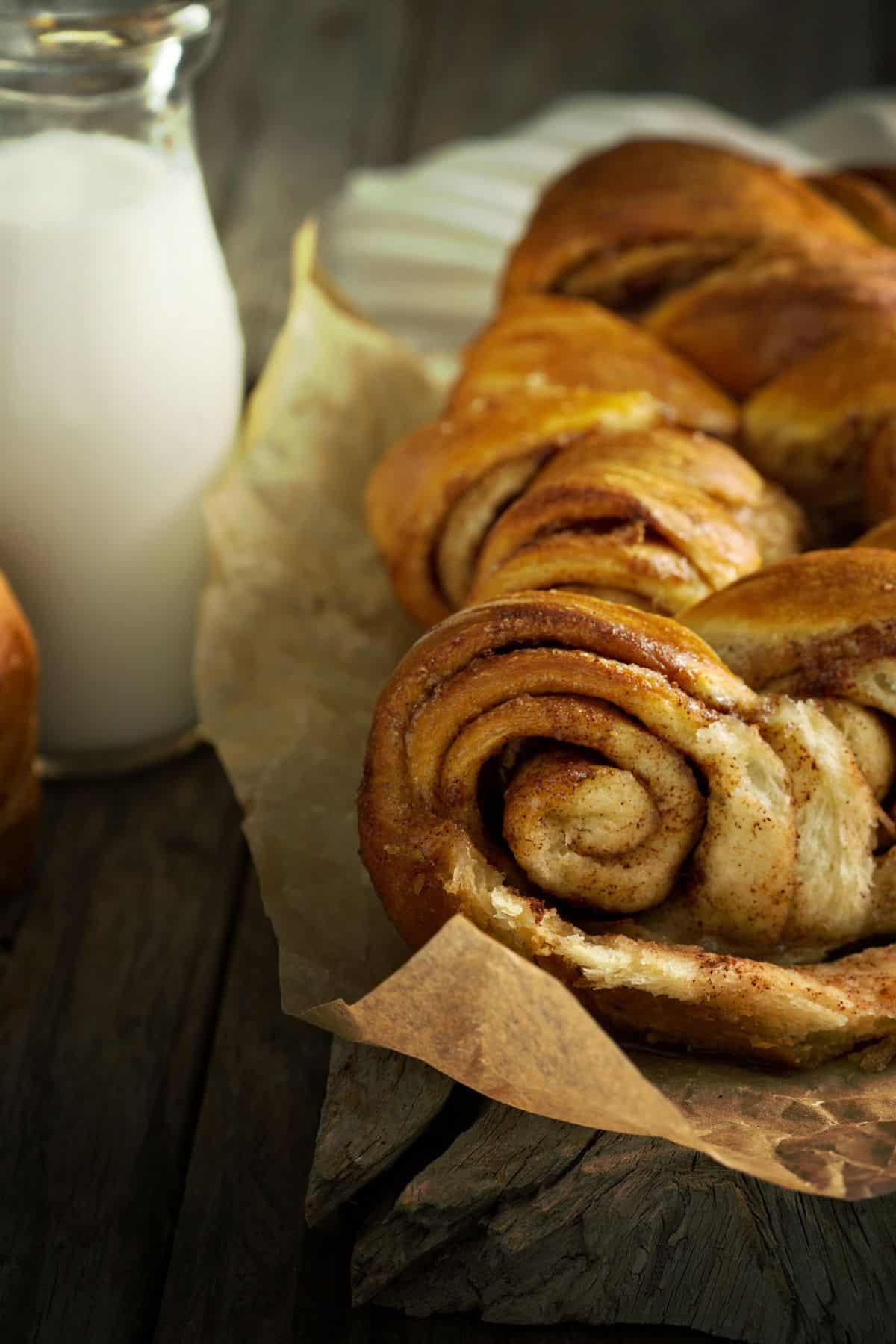 Close up of a loaf of cinnamon pull-apart bread, warm and fresh from the oven, sitting beside a glass of milk waiting to be shared!