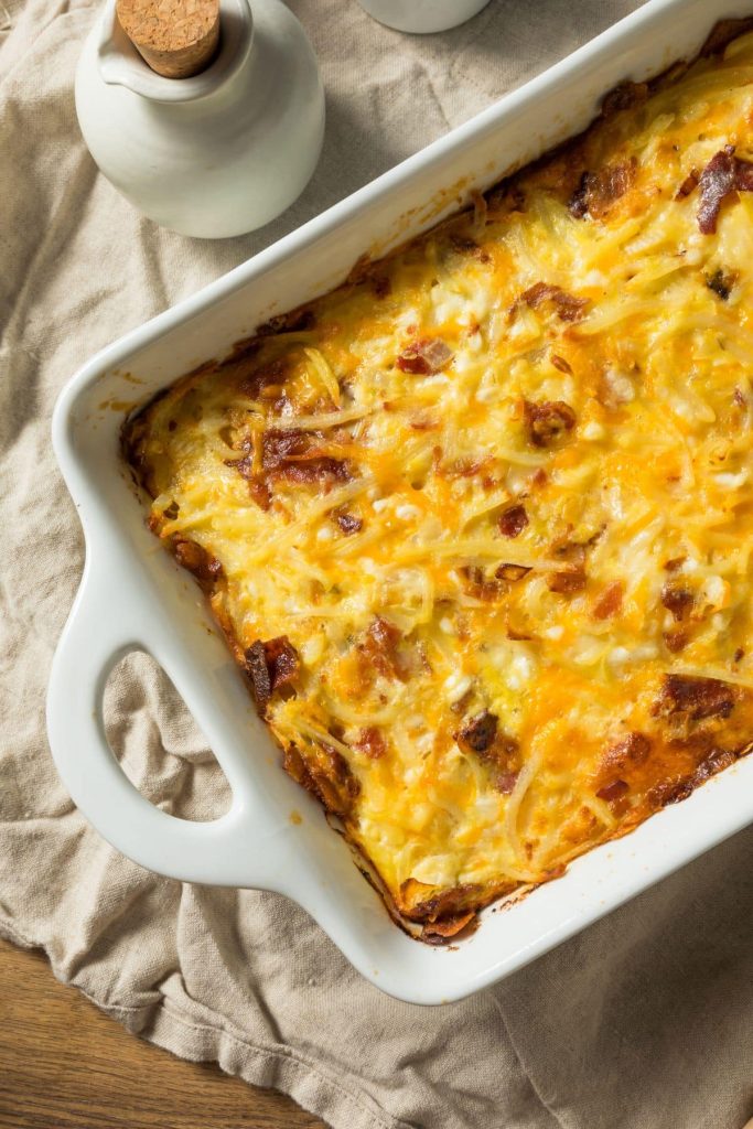 Close up of a cheesy, protein-rich breakfast casserole in a white baking dish