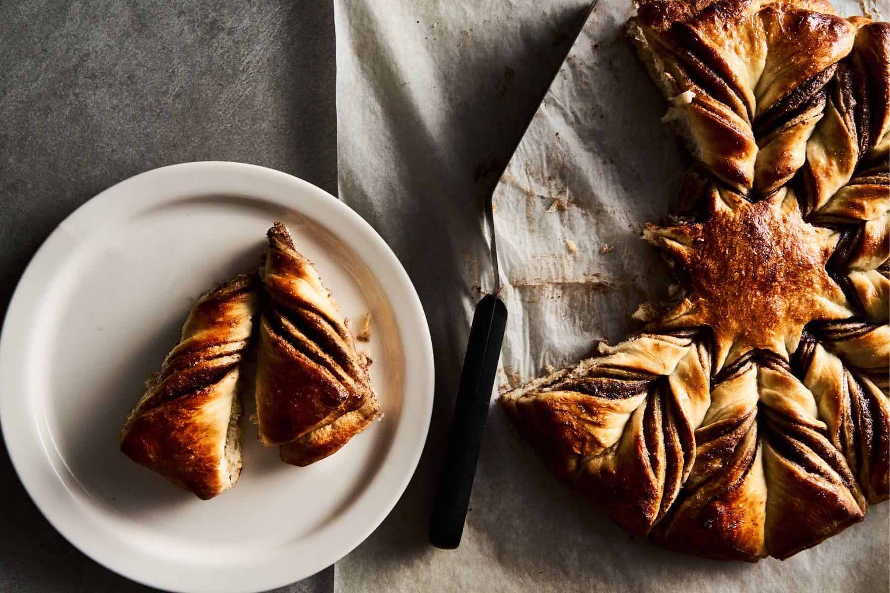 Close up of a sourdough Nutella star bread-fluffy, rich, and delicious-with two pieces torn off and sitting on a plate waiting to be enjoyed!