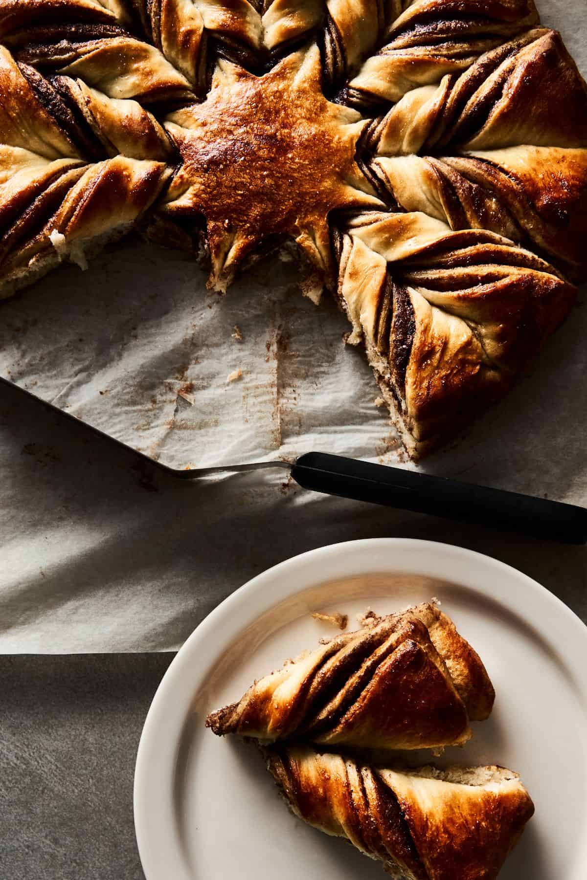 Close up of a sourdough Nutella star bread-fluffy, rich, and delicious-with two pieces torn off and sitting on a plate waiting to be enjoyed!