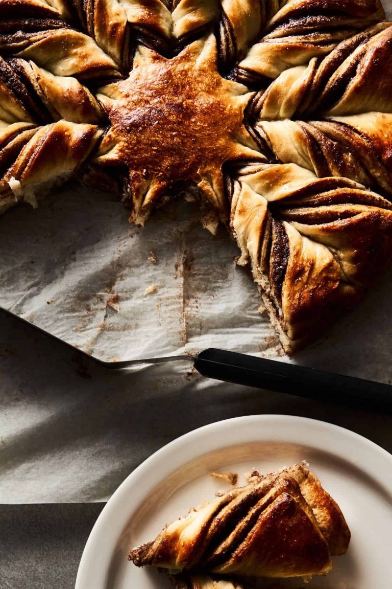 Close up of a sourdough Nutella star bread-fluffy, rich, and delicious-with two pieces torn off and sitting on a plate waiting to be enjoyed!