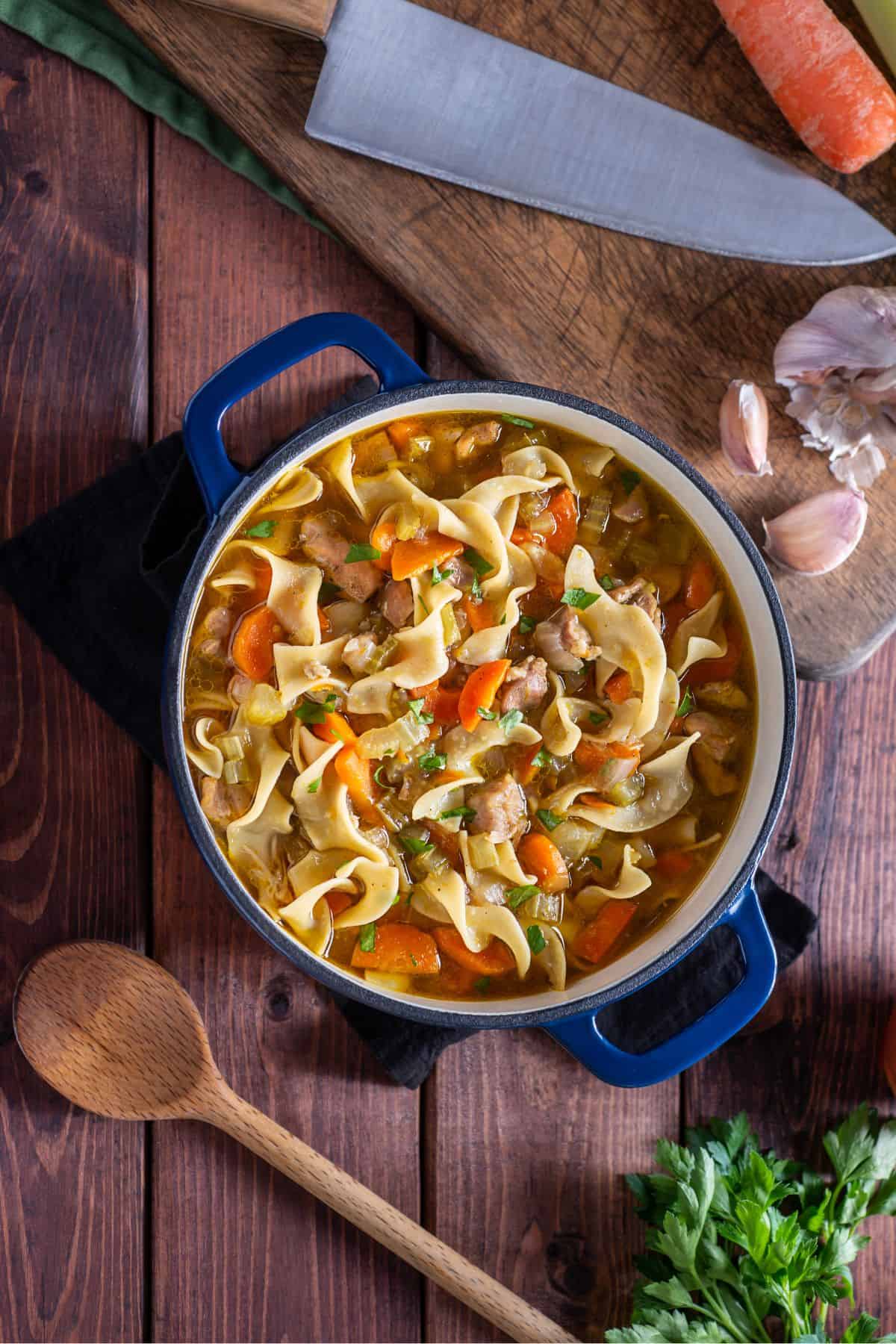 Homemade chicken noodle soup from scratch in a large blue dutch oven