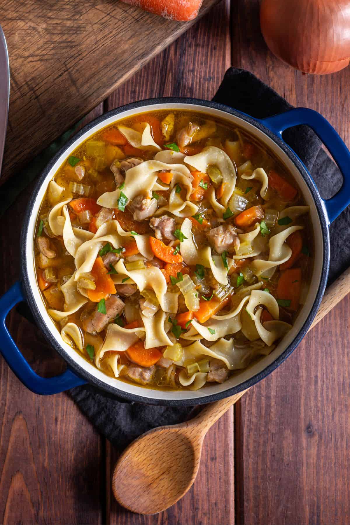Homemade chicken noodle soup from scratch in a large blue dutch oven