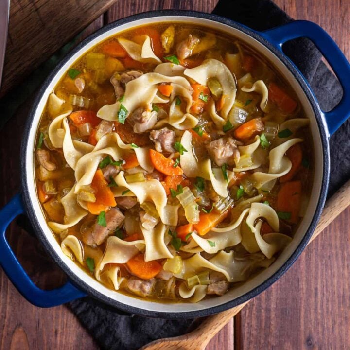 Homemade chicken noodle soup from scratch in a large blue dutch oven