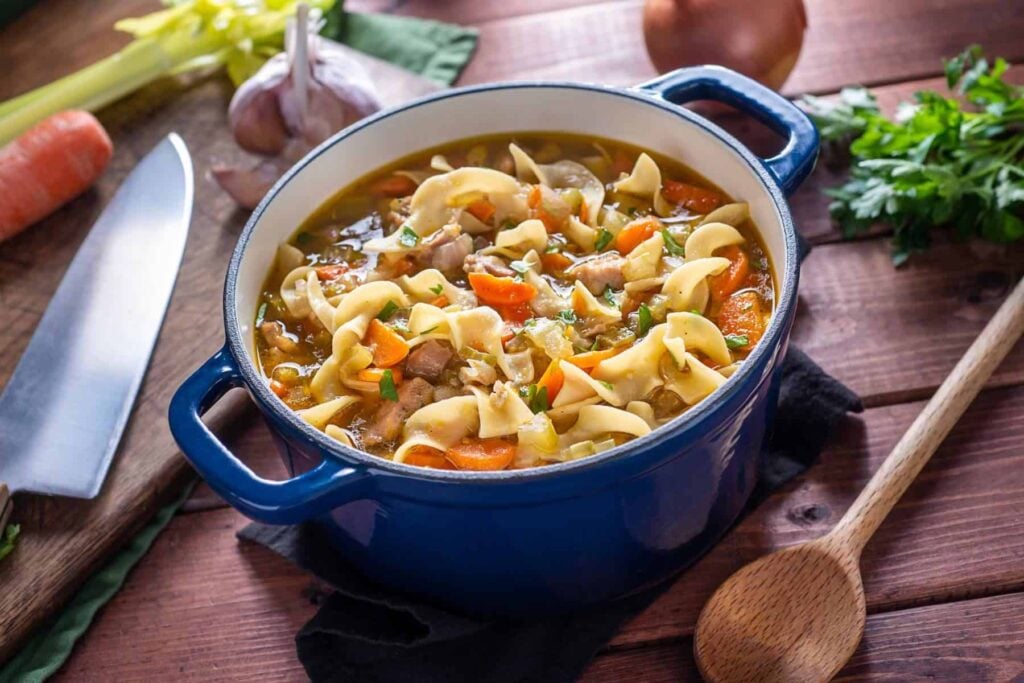 Homemade chicken noodle soup from scratch in a large blue dutch oven