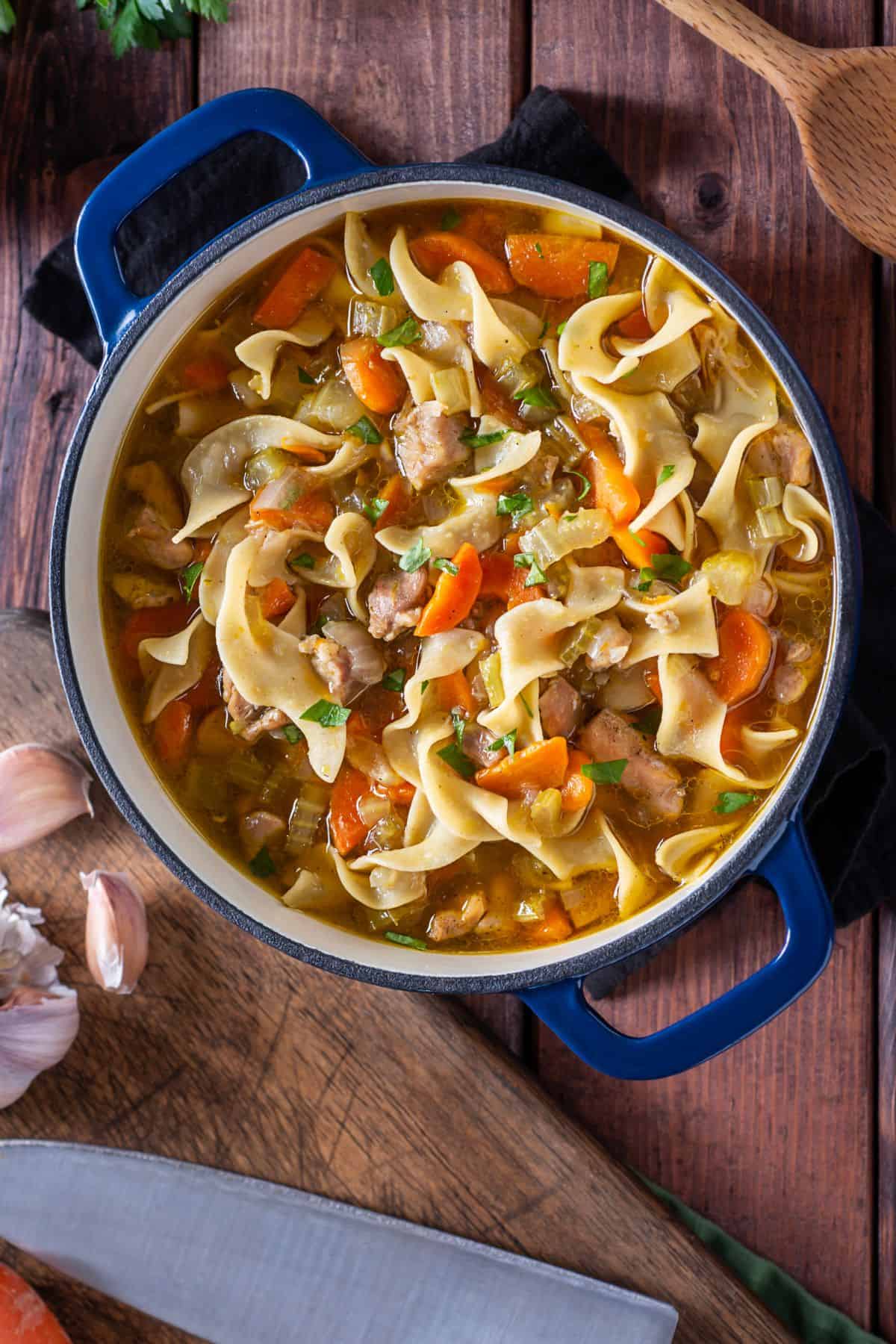 Homemade chicken noodle soup from scratch in a large blue dutch oven