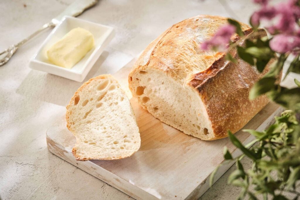 King Arthur Sourdough on a wooden board, sliced with butter beside it - ready to eat.