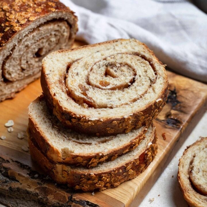 Sliced sourdough cinnamon raisin swirl bread on a wooden cutting board