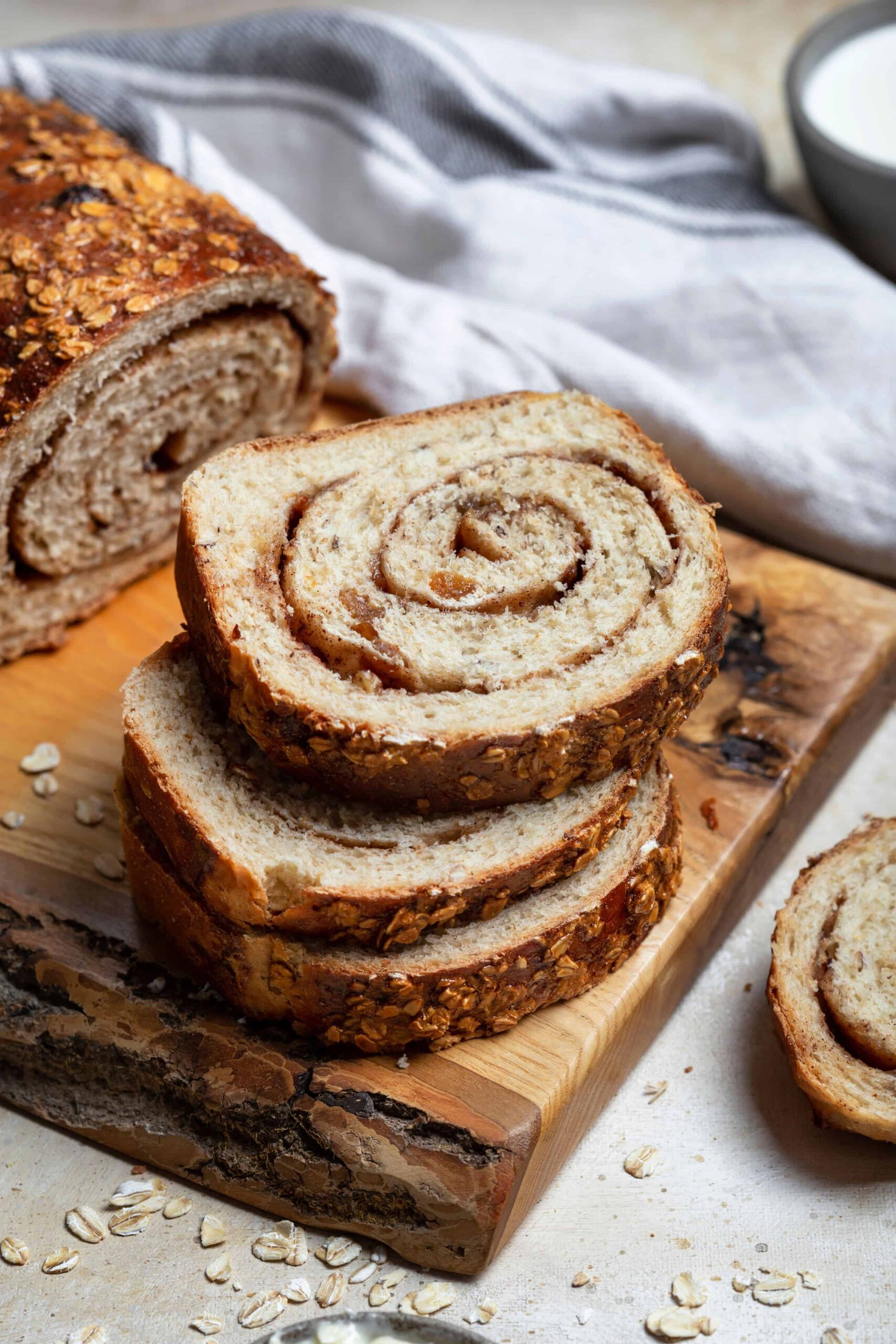 Sliced sourdough cinnamon raisin swirl bread on a wooden cutting board