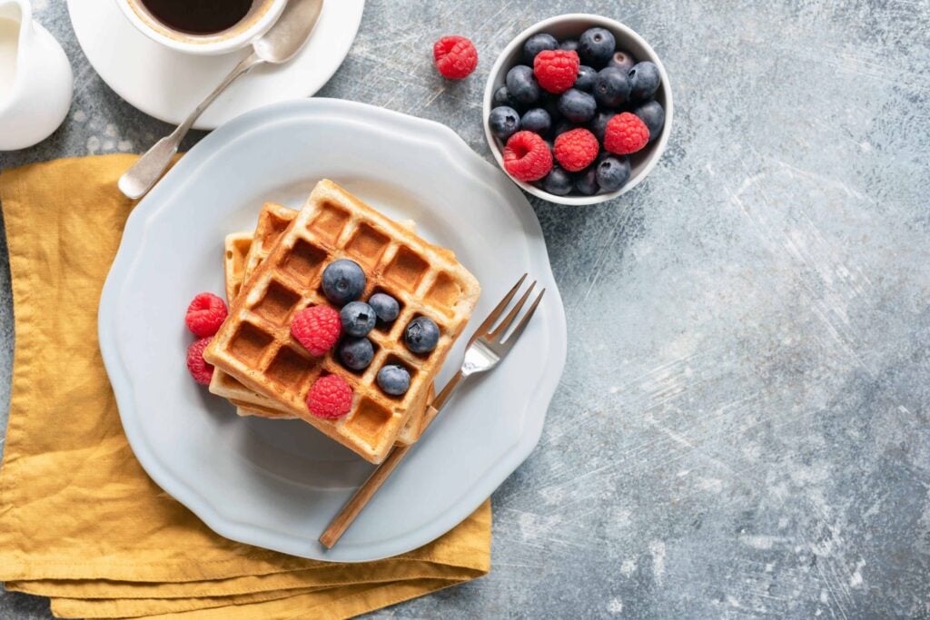 Close up of whole wheat waffles with fresh berries rand coffee - ready to eat.
