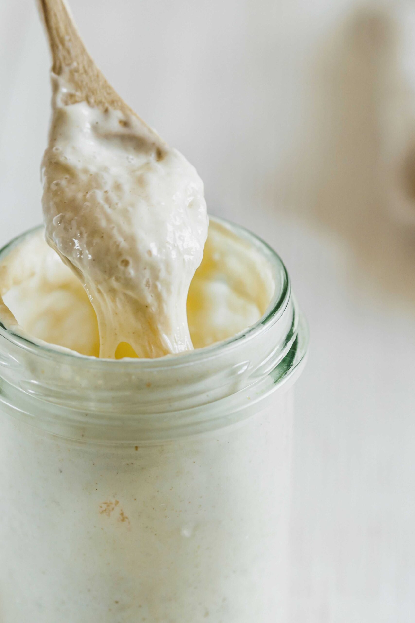 Jar of bubbly sourdough starter being spooned out to freeze