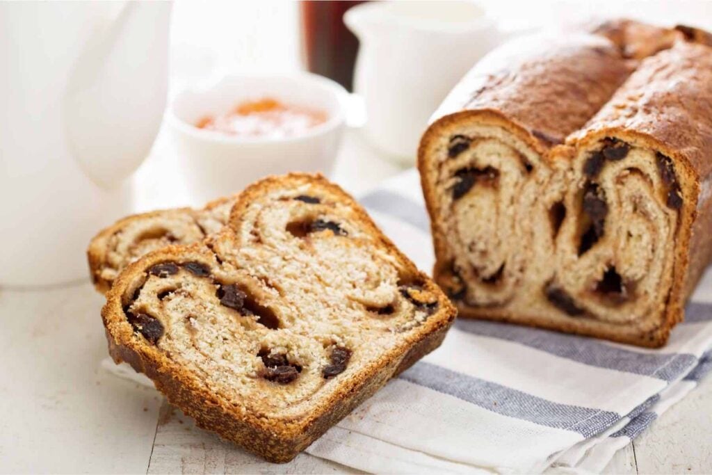 Whole wheat cinnamon raisin loaf sliced on a blue and white tea towel