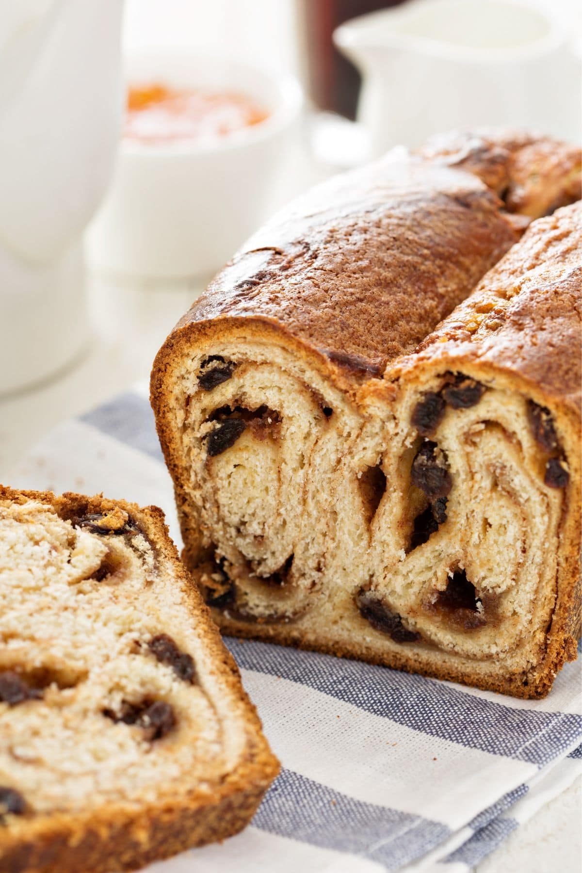 Whole wheat cinnamon raisin loaf sliced on a blue and white tea towel