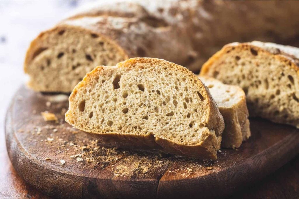 Close up of sliced whole wheat baguette recipe on a wooden cutting board
