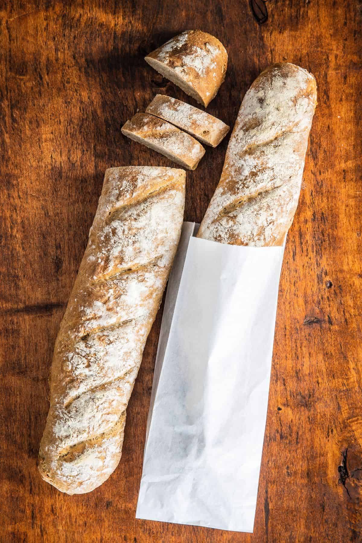 Whole wheat baguette recipe baked and in paper for sharing.