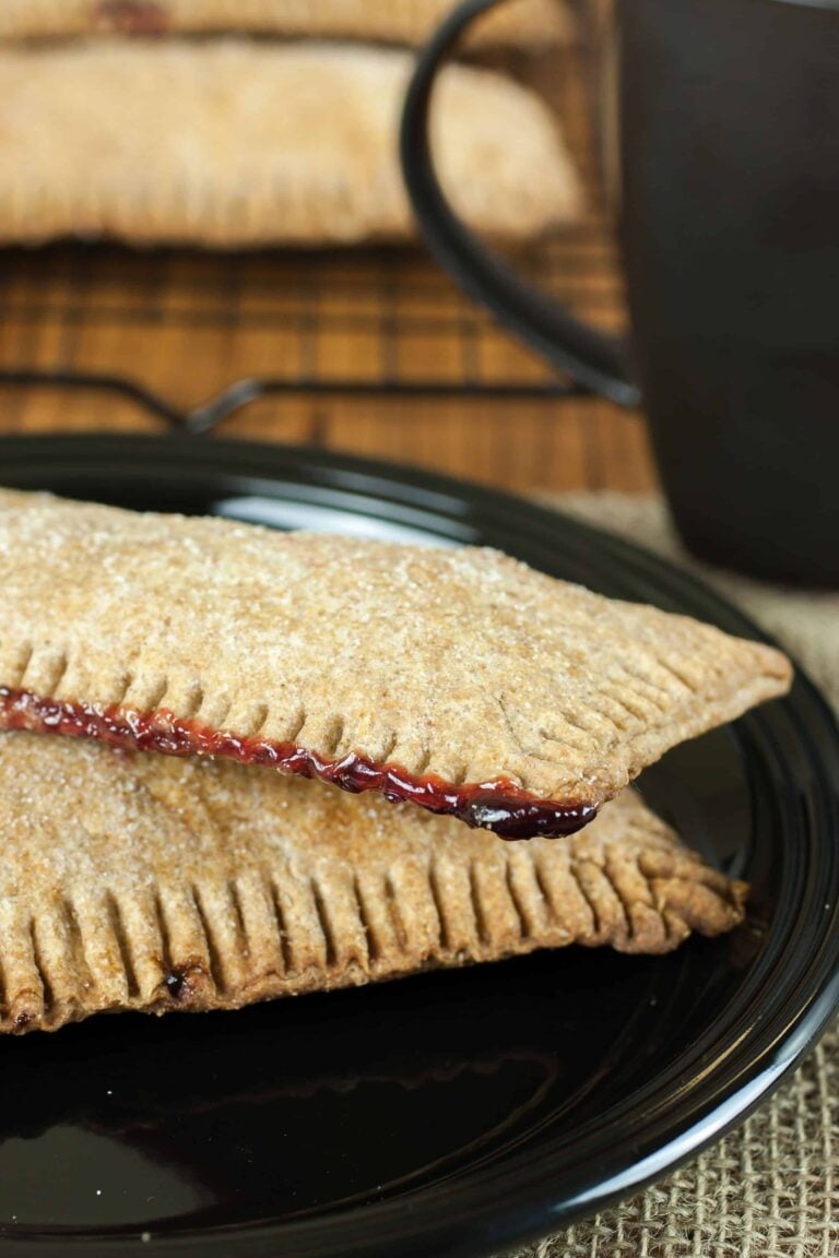 Fresh milled flour pop tarts with raspberry filing on a plate beside a cup of coffee