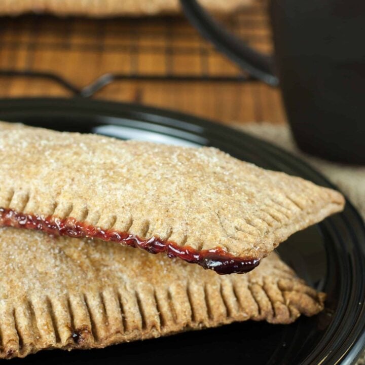 Fresh milled flour pop tarts with raspberry filing on a plate beside a cup of coffee