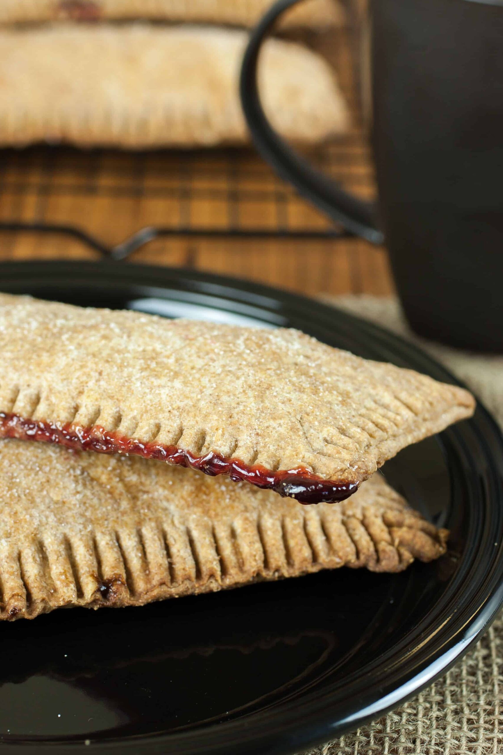Fresh milled flour pop tarts with raspberry filing on a plate beside a cup of coffee