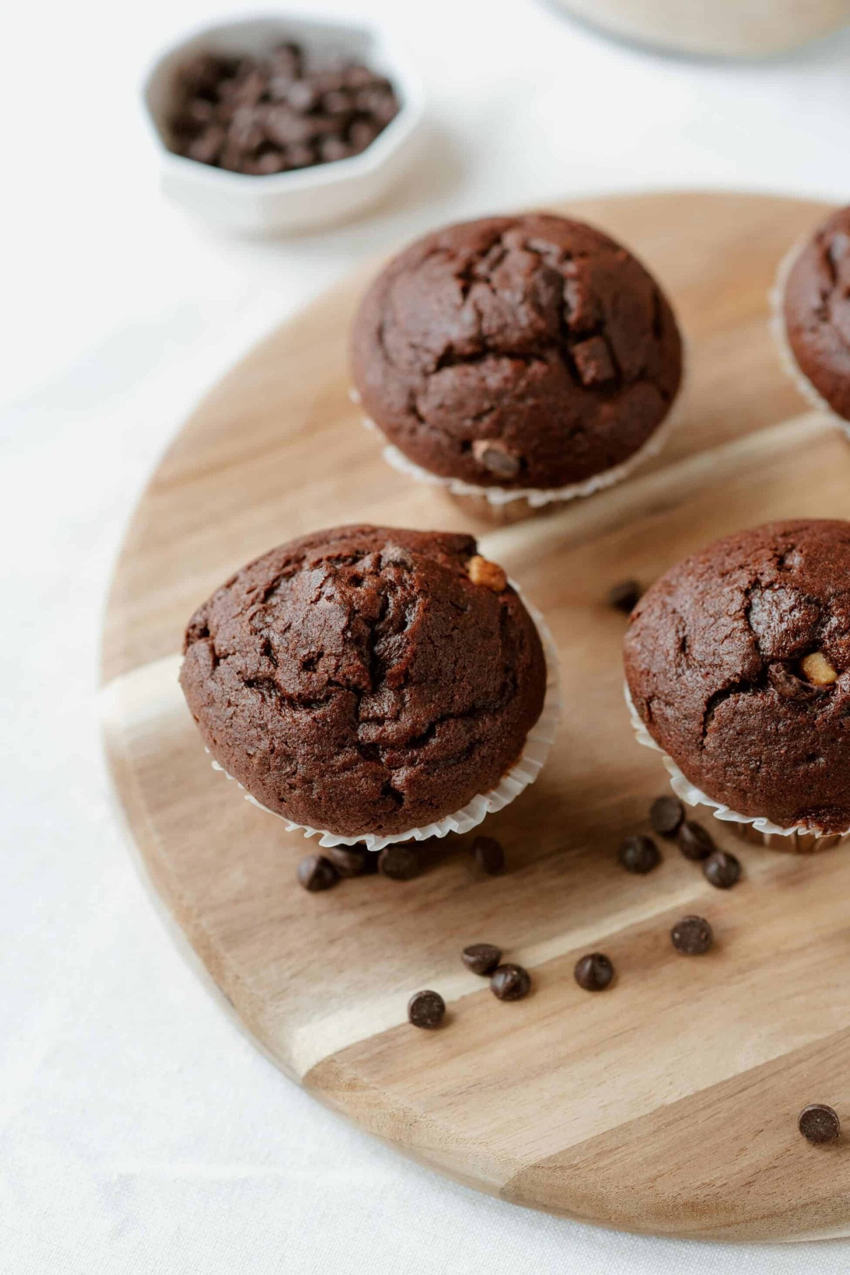 Gooey whole wheat chocolate muffins on a cutting board with chocolate chips