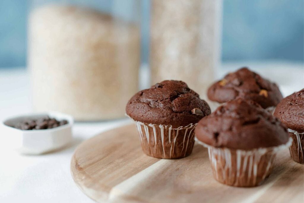 Whole wheat chocolate muffins on a board waiting to be enjoyed.