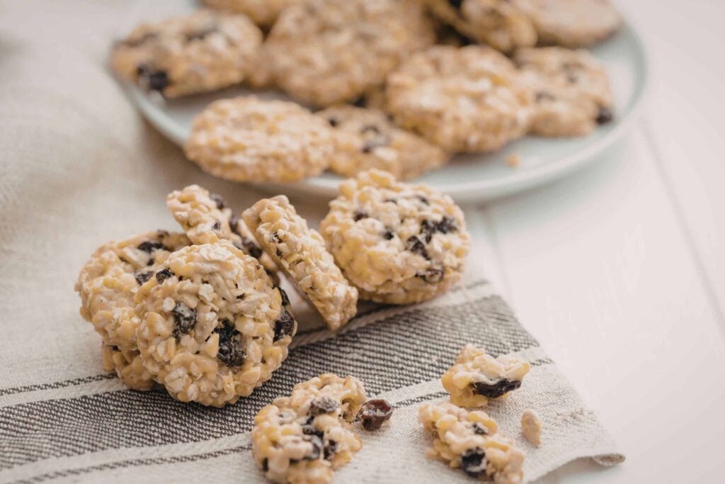 Freshly baked oatmeal raisin cookies on a tea towel.