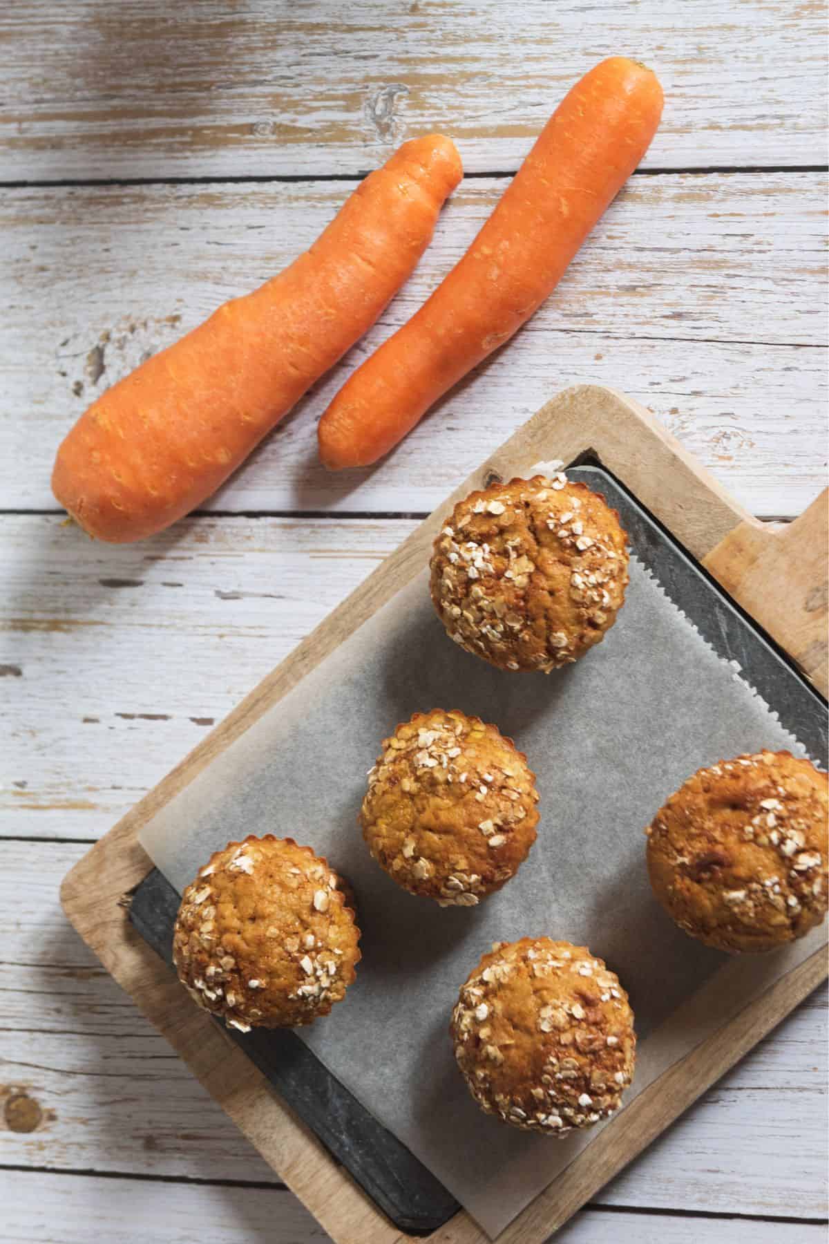 Whole wheat carrot muffins on a tray with carrots