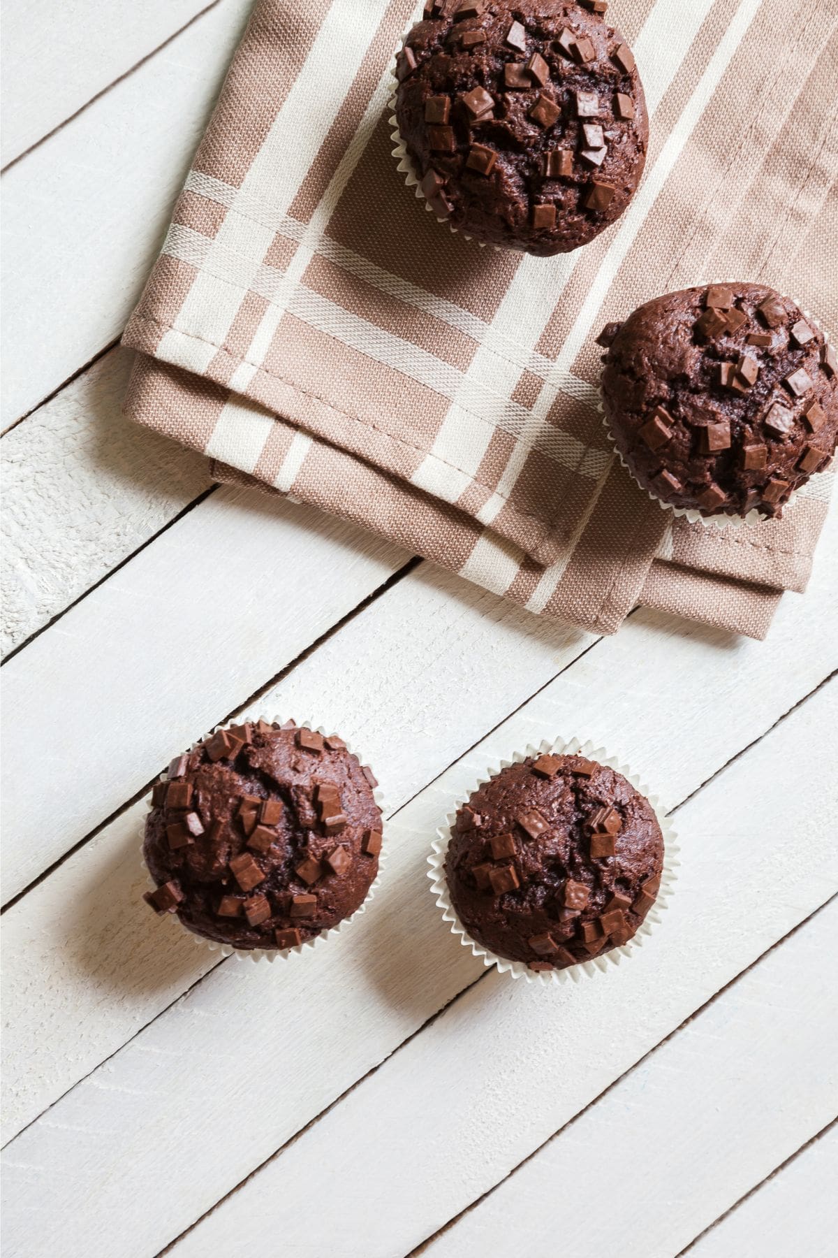 Whole wheat chocolate muffins cooling on a tea towel.