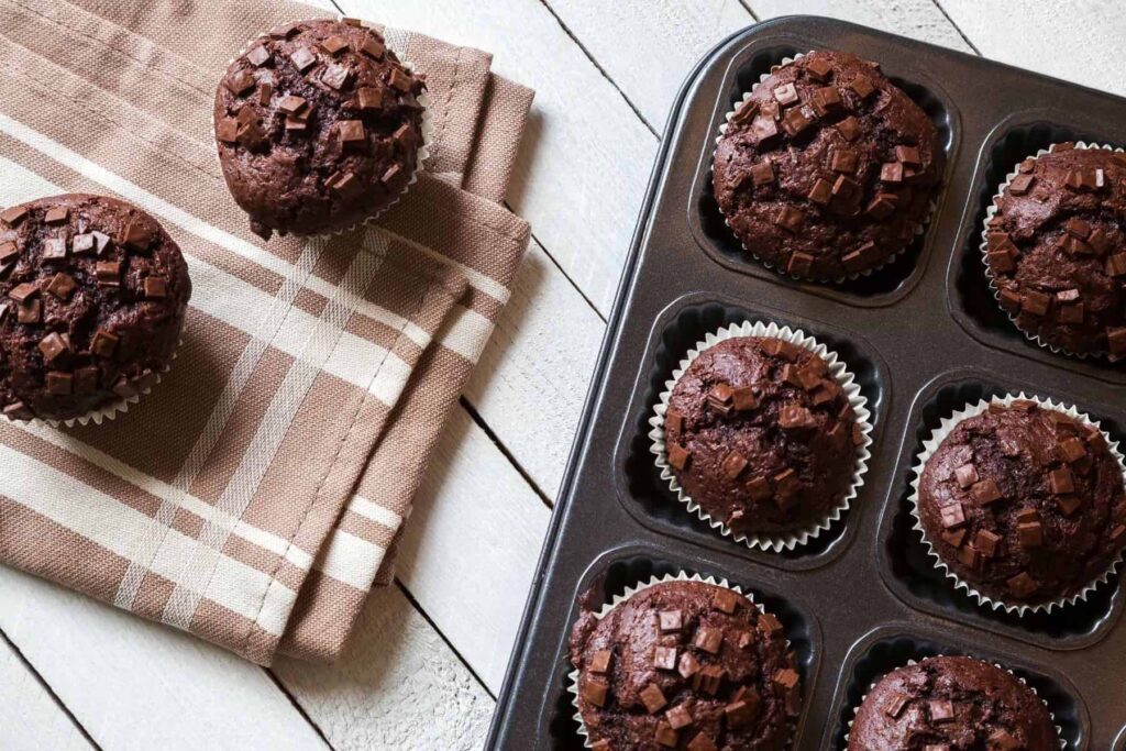 Freshly milled chocolate zucchini muffins cooling on a tea towel