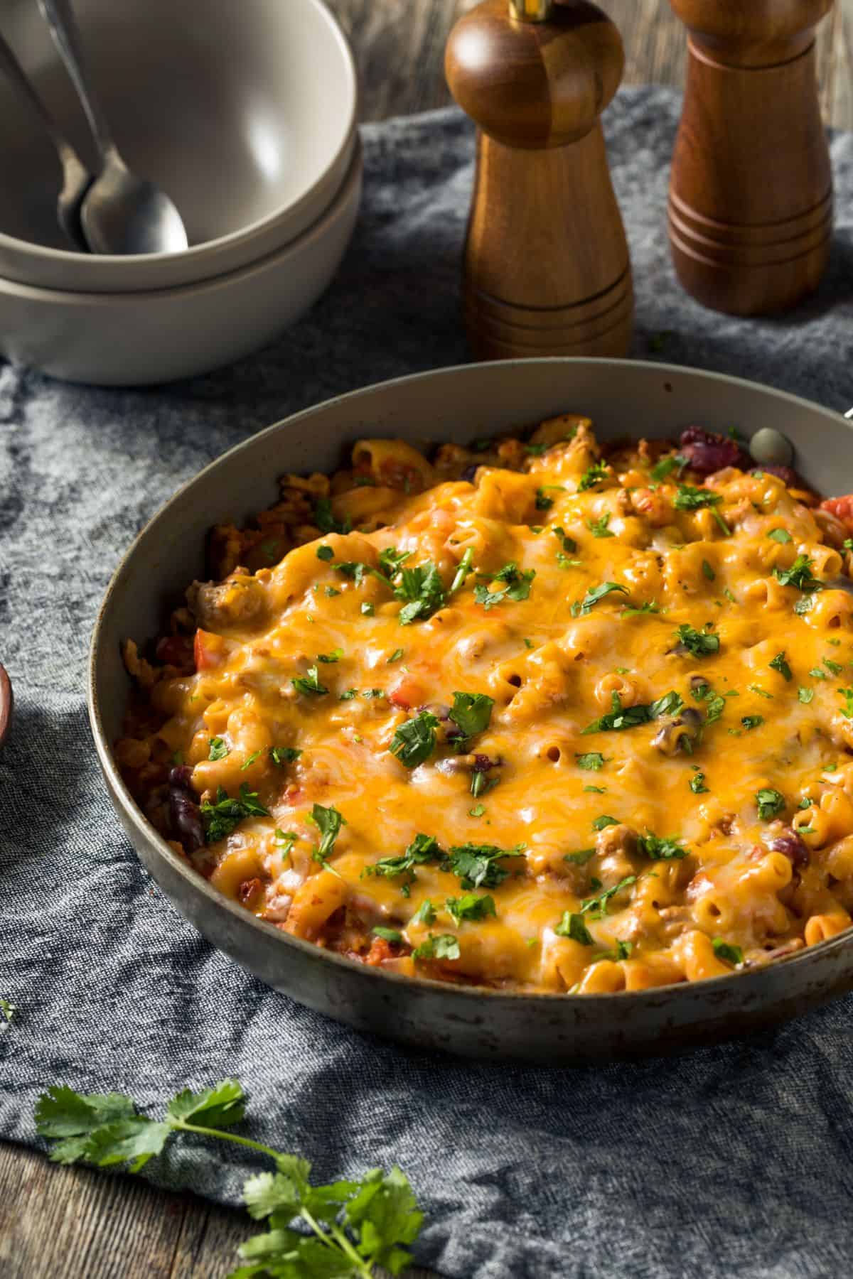 Skillet of turkey taco chili mac covered in cheese and fresh herbs